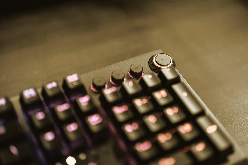Close-up of a backlit gaming keyboard glowing purple and red in a dark room