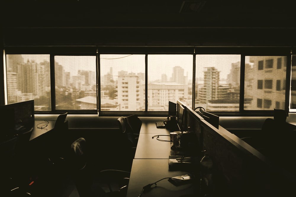 A game studio office with rows of desks and monitors overlooking a city skyline